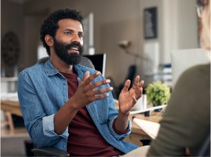 A young man is talking and gesticulating with open palms to som A young man is talking and gesticulating with open palms to someone off screen
